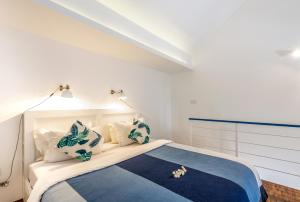 塞米亚克The Blue Loft Seminyak free scooter的一间卧室配有一张带蓝色和白色枕头的床