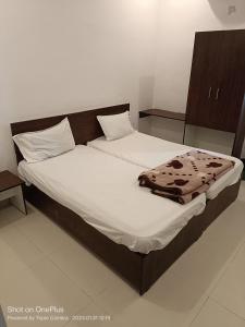 卡努尔Durga Pride的一张带白色床单的床,一张毯子