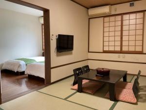 屋久岛绳文之宿蔓藤酒店的客房设有1张床、1张桌子和1台电视。
