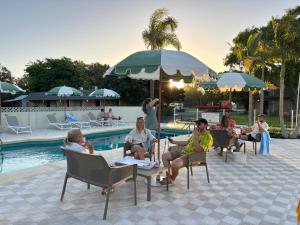 巴瑟尔顿The Timothée Resort的一群人坐在游泳池边的椅子上