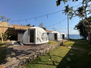 库布Glamping @ Pebbles & Fins的三个帐篷在海边的石墙上