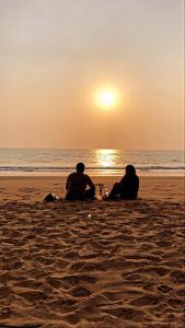 戈卡尔纳Blue Lagoon Redefined的两人坐在海滩上欣赏日落