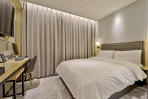 釜山Hotel Brooks Busan Gijang的酒店客房配有一张床、一张书桌和一台电视。