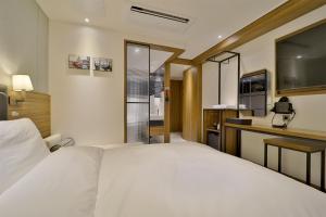 釜山Hotel Brooks Busan Gijang的一间带白色床的卧室和一间厨房