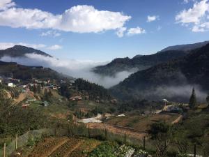 Sa PảScenic Views Farmstay And Hostel Sapa的享有山谷和群山云的景色