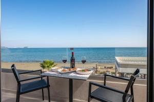 拉加纳斯Horizon Beachfront Apartments的沙滩上一张桌子,上面放着酒杯和一盘食物