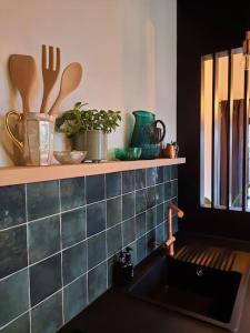 胡伊埃拉尔特Ateljee Sohie的厨房配有水槽和带餐具的架子