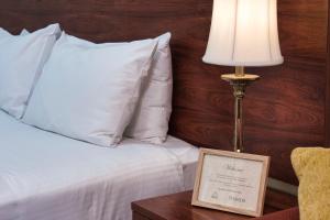 肯图巴肯图巴大都会宾馆的一张带白色枕头的床和一张桌子上的台灯