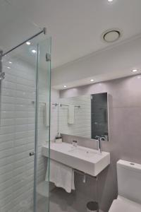 约翰内斯堡ONOMO Hotel Johannesburg Sandton的一间带水槽和玻璃淋浴的浴室