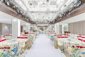 巴中平昌香榭里智选假日酒店的宴会厅配有白色的桌子和蓝色的鲜花
