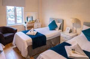 牛津OYO Lonsdale Guest House的一间卧室设有两张床、一把椅子和一个窗户。