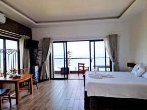 富国Butterfly Rose Beach Resort Phú Quốc Francophone的一间卧室配有一张床铺和一张桌子,并设有一个阳台