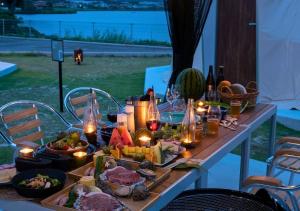 出云市Glamping Base IZUMO "Lakeside Hot Spring Hotel Kun - Vacation STAY 42019v的一张桌子,上面放着食物、蜡烛和葡萄酒