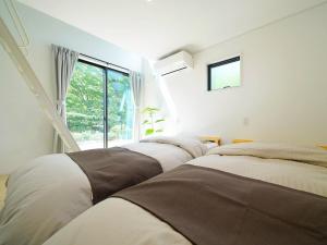 上田市SENKO TINY CAMP - Vacation STAY 85298v的一间卧室设有三张床和窗户。