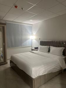 达曼الساعه 60 الفندقيه的一张大白床,位于带灯的房间