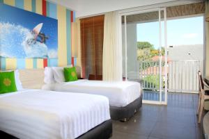 勒吉安Bliss Surfer Hotel by Tritama Hospitality的两间床铺,位于酒店房间,配有冲浪者