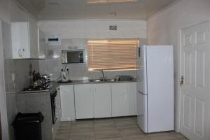 帕罗Three Arches Guesthouse的厨房配有白色橱柜和白色冰箱。