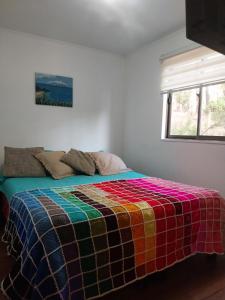 瓦尔帕莱索Laguna Verde Valparaiso的一张床上的房间,上面有五颜六色的毯子