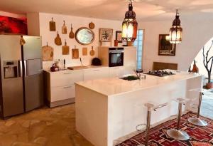 滨海卡瓦莱尔Villa Hirondelles 35的厨房配有冰箱和带凳子的台面