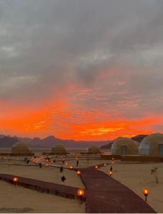 瓦迪拉姆Wadi rum anwar luxury camp的 ⁇ 顶和灯光的地野上的日落