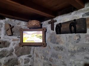 坎加斯-德奥尼斯Casa Rural El Cotu en Cangas de Onís的石墙上的电视,带十字架和篮子