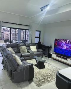 米德兰Munyaka Lagoon Penthouse的客厅配有真皮沙发和平面电视