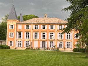 佩兹纳斯Château de Roquelune的一座大型橙色建筑,设有大型草地庭院