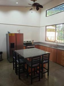 TirimbinaLoma Linda Sarapiquí Casa Nueva NEW HOUSE 3bed/2bath的厨房配有桌子、椅子和冰箱。