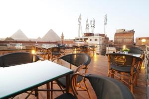 开罗Locanda Pyramids Hotel的屋顶上一排有金字塔的桌椅