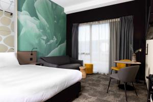 罗森达尔Otium Hotel Roosendaal的配有一张床和一把椅子的酒店客房