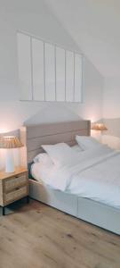 尼翁Coco Marco Hôtel的卧室配有白色的床和带两盏灯的床头柜。