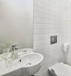 华沙Bez Kantów Art Rooms的白色的浴室设有水槽和卫生间。