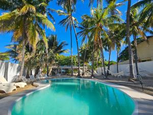 拉利伯塔德Sunset Surf Villa的一个带棕榈树和躺椅的游泳池