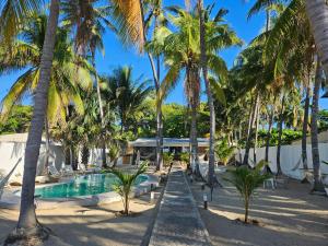 拉利伯塔德Sunset Surf Villa的一个带游泳池和棕榈树的度假村