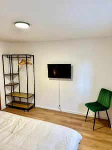 布雷根茨Stilvolles Wohnen am Hafen的卧室配有绿色椅子和墙上的电视