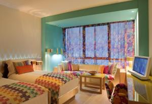 科威特Symphony Style Hotel Kuwait的一间卧室配有一张床、一张沙发和一个窗口