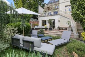 丰特奈苏布瓦Villa des Oliviers的后院设有椅子和遮阳伞,还有房子