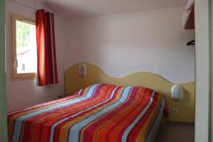 阿雷斯maisonnette 6 pers dans résidence avec piscine的一间卧室配有一张带彩色条纹毯子的床