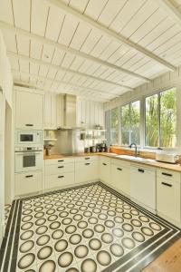 卡普费雷CABANE JASMIN au CAP FERRET的厨房配有白色橱柜和瓷砖地板。