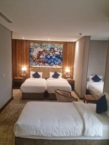 吉达EWG Golden Sea Hotel Obhur的酒店客房设有三张床,墙上挂有绘画作品