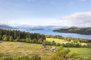 巴洛赫Stoneymollan over Loch Lomond的享有湖泊和田野房屋的空中景色