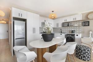 布鲁堡史特兰Coral Island 204的白色的厨房配有桌子和白色椅子