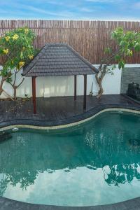 登巴萨Private Urban Villa Denpasar的木甲板,毗邻带凉亭的游泳池