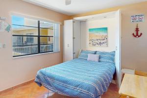 好莱坞The Boardwalker的一间卧室配有一张带蓝色棉被的床和窗户。