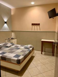 尼泰罗伊Hotel Glória的一间卧室配有一张床、一张桌子和一台电视。