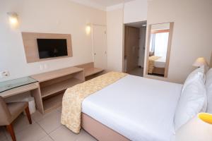 萨尔瓦多贝罗翁迪纳普拉亚酒店的一间卧室配有一张床、一张书桌和一台电视