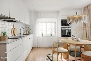 斯德哥尔摩Central beautiful modern accommodation near Stockholm City的厨房配有白色橱柜和木桌