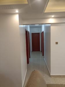 内罗毕Home Croft Nairobi的一条带白色墙壁和红色门的走廊