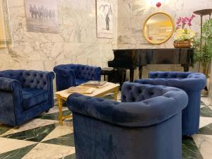 乌尔比诺Hotel Raffaello - Self Check-in Free的一间设有蓝色椅子、一张桌子和钢琴的房间