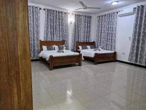 Mbweni64 ZENJ HOUSE Luxury Airport B&B的一间卧室配有两张床和窗帘
